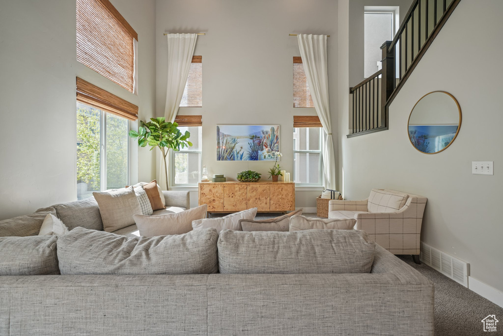 Living area featuring a towering ceiling, carpet floors, and stairway