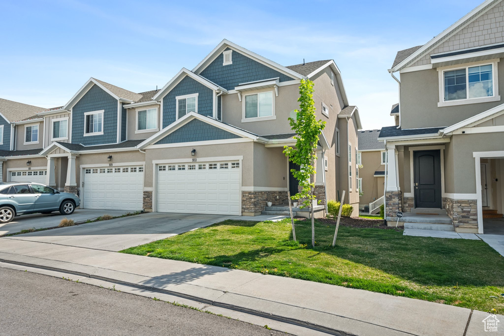 Craftsman inspired home with stone siding, concrete driveway, a front lawn, stucco siding, and a garage