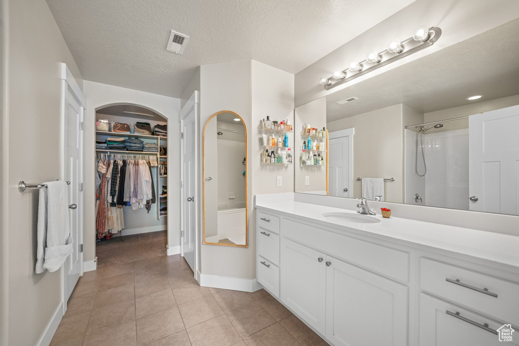 Bathroom featuring vanity, a walk in closet, a shower, and tile patterned floors