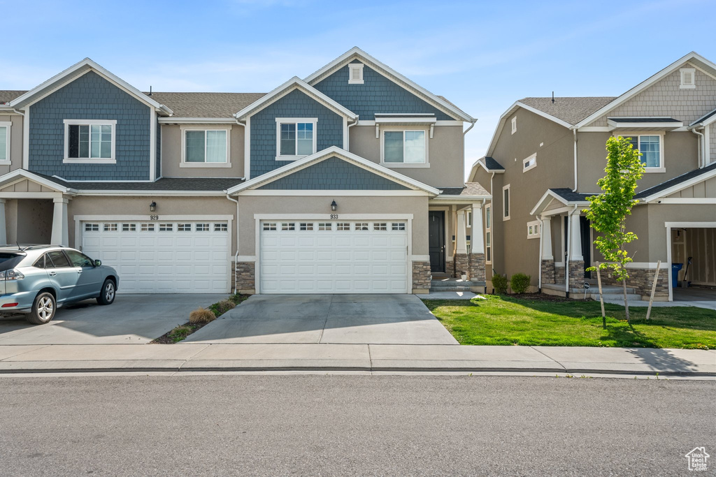 Craftsman-style house with driveway, stone siding, and an attached garage