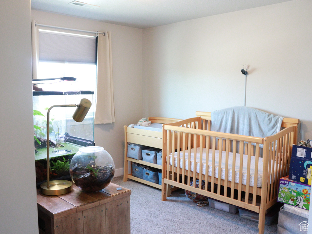 Carpeted bedroom featuring a crib