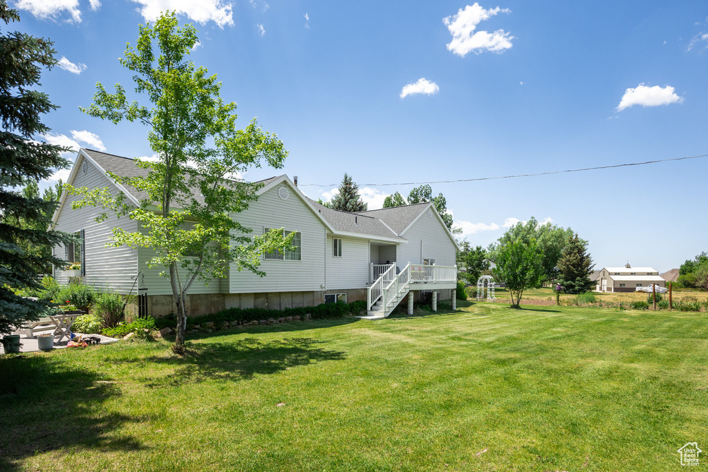 Back of property featuring stairs, roof with shingles, a yard, and a deck