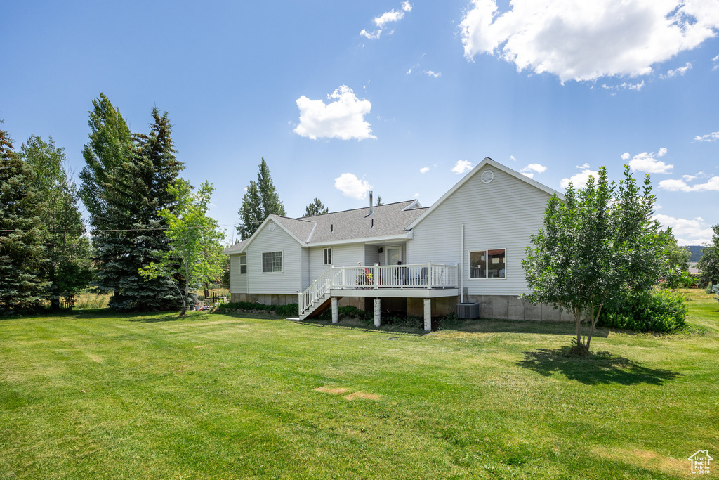 Back of property with a yard, a deck, and stairway