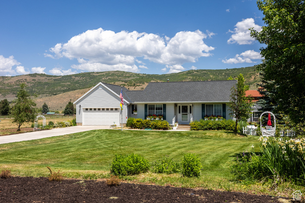 Ranch-style house featuring driveway, a mountain view, an attached garage, and a front yard