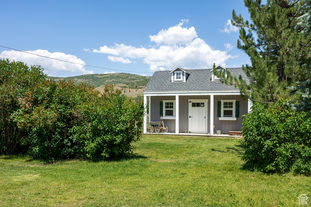 View of front of house with a shingled roof, a front yard, and a porch