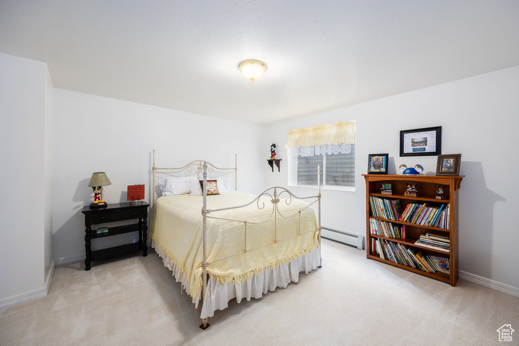Bedroom featuring light carpet and a baseboard heating unit