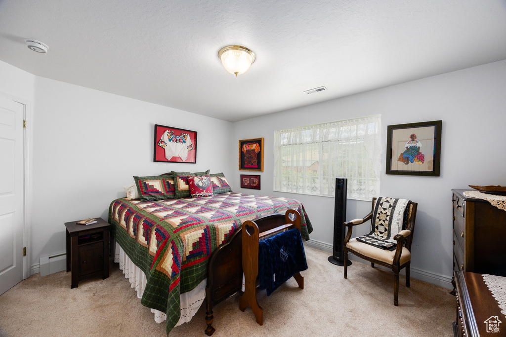 Bedroom with light colored carpet and a baseboard radiator