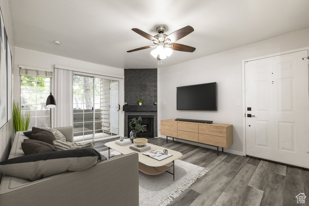 Living area featuring wood finished floors, ceiling fan, and a fireplace