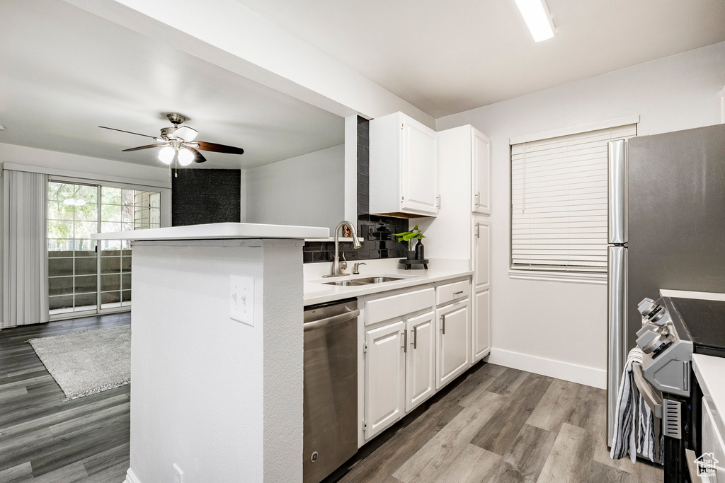 Kitchen with appliances with stainless steel finishes, wood finished floors, a ceiling fan, white cabinets, and light countertops