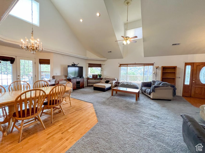 Dining space featuring high vaulted ceiling, recessed lighting, light wood-type flooring, ceiling fan, and a chandelier