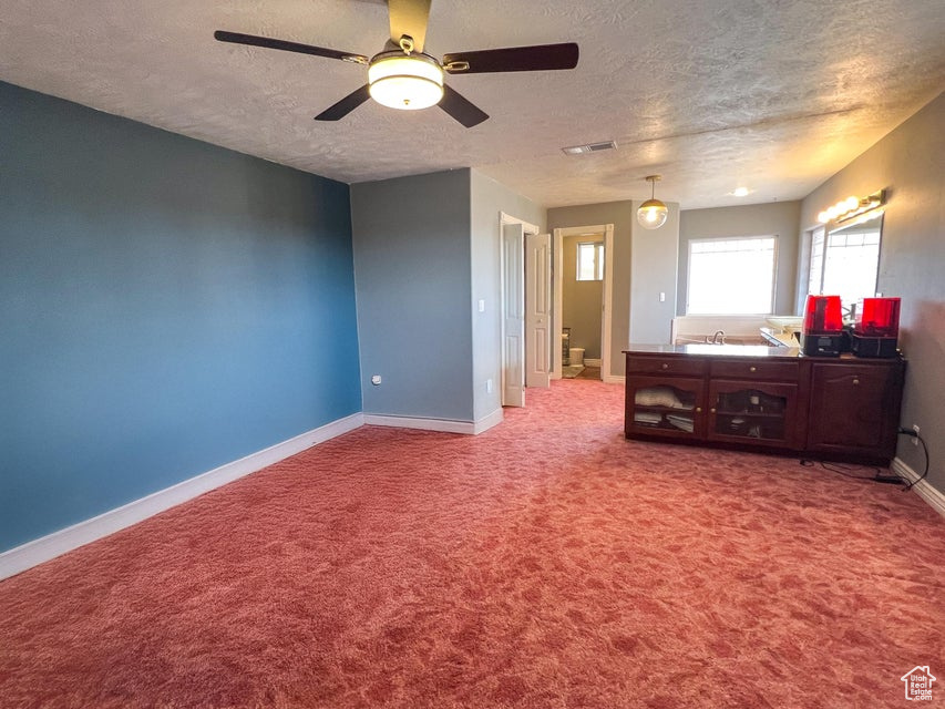 Carpeted bedroom featuring a textured ceiling and a ceiling fan