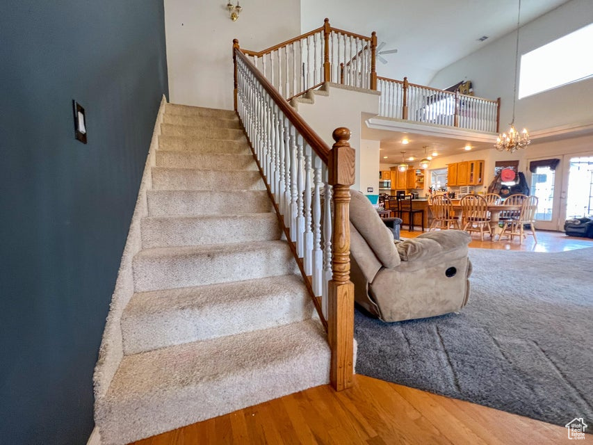 Staircase featuring a high ceiling, wood finished floors, and a chandelier