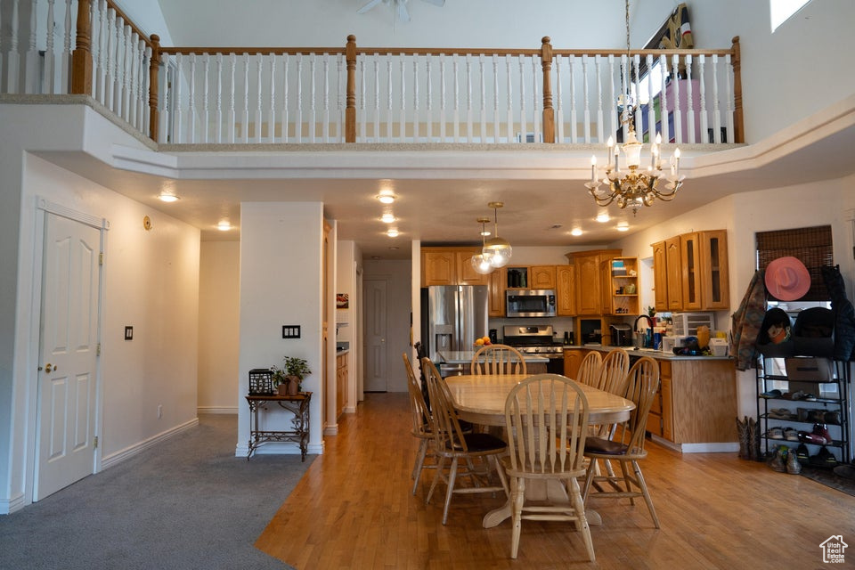 Dining room with a high ceiling, a chandelier, and light wood-style floors
