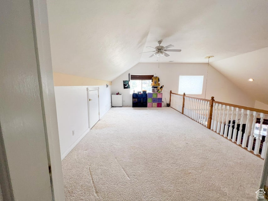 Additional living space featuring a ceiling fan, vaulted ceiling, and carpet floors