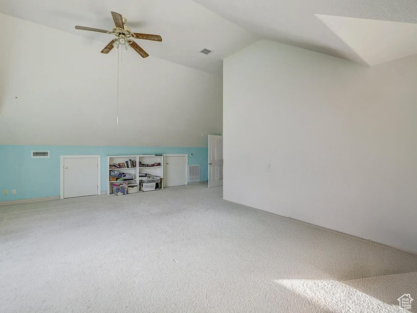 Additional living space with vaulted ceiling, light carpet, and ceiling fan