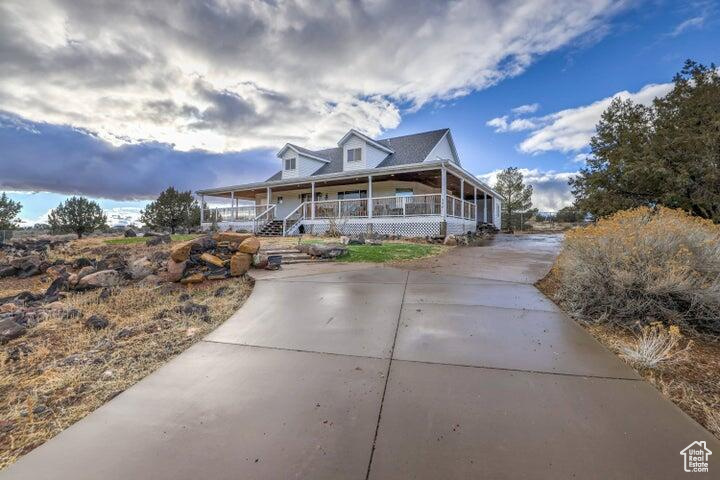 Country-style home featuring a porch and concrete driveway