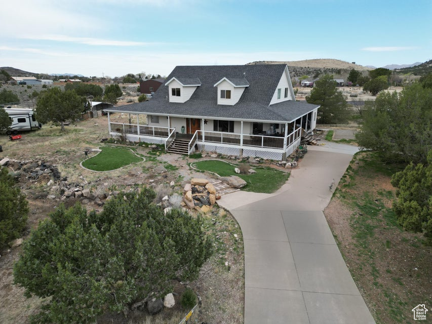 Farmhouse-style home featuring concrete driveway, a porch, and a shingled roof