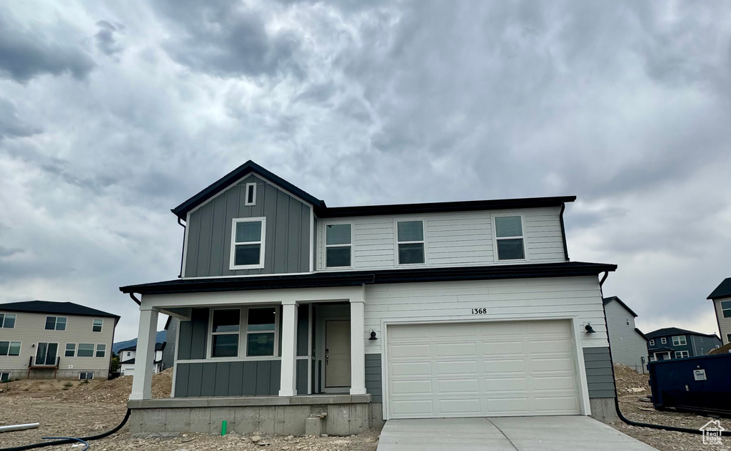 View of front of property with covered porch, board and batten siding, driveway, and an attached garage