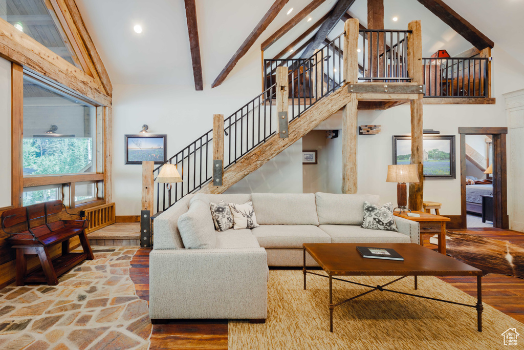 Living area with beamed ceiling, wood finished floors, high vaulted ceiling, stairs, and recessed lighting