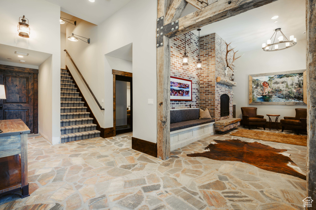 Foyer entrance with a towering ceiling, stone flooring, stairway, and a fireplace