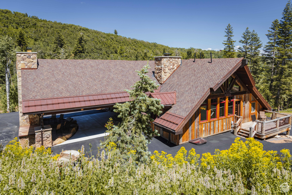 Rear view of house with a chimney, a standing seam roof, a wooded view, and a metal roof