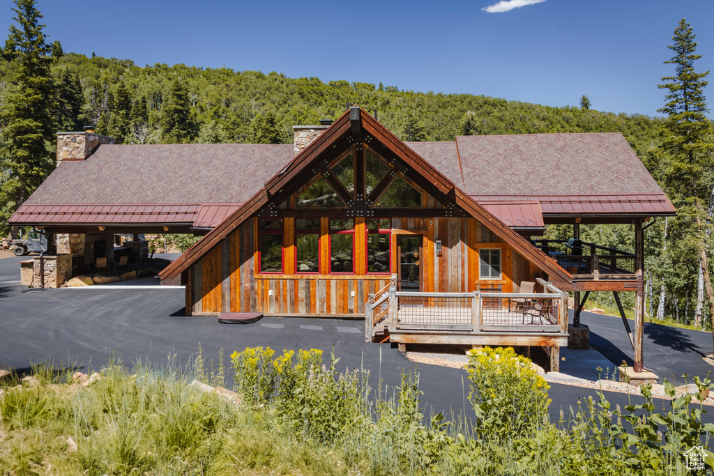 View of front facade with a standing seam roof, a chimney, a forest view, and a metal roof