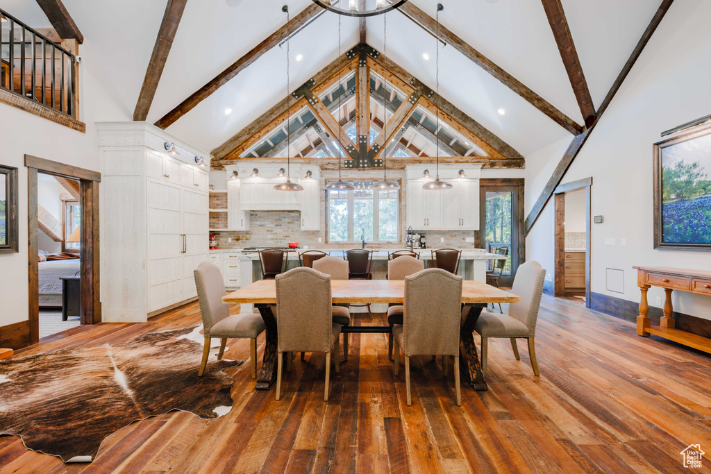 Dining area with hardwood / wood-style floors, beamed ceiling, and high vaulted ceiling