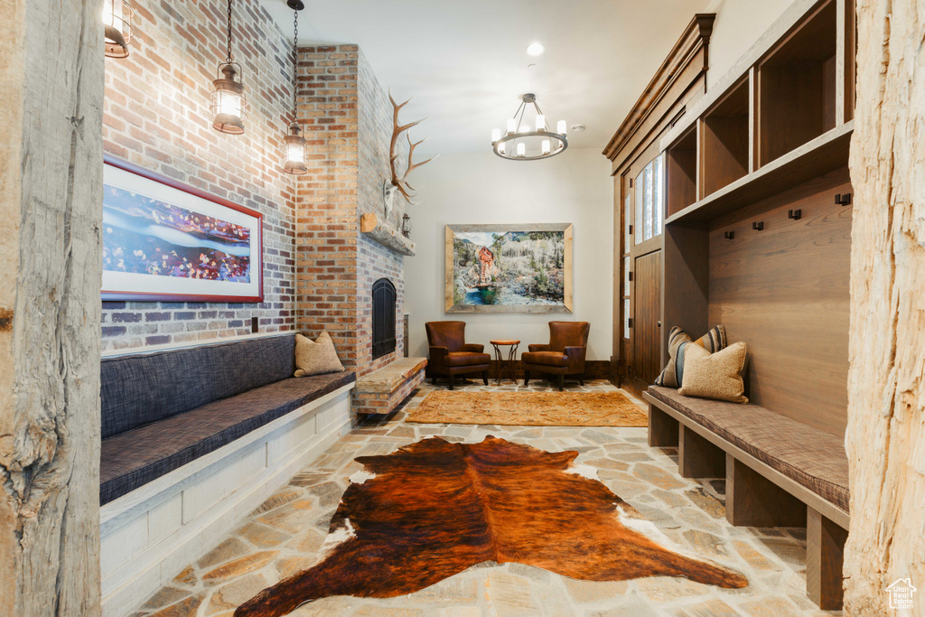 Mudroom with stone flooring, a fireplace, and a chandelier