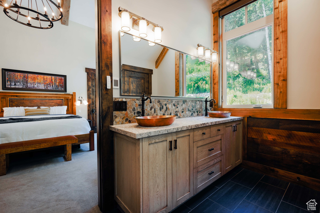 Bathroom with plenty of natural light, double vanity, decorative backsplash, and a chandelier