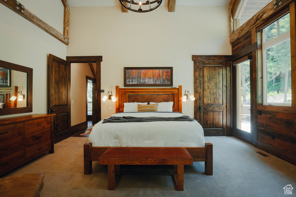 Bedroom with a towering ceiling, light carpet, and access to exterior