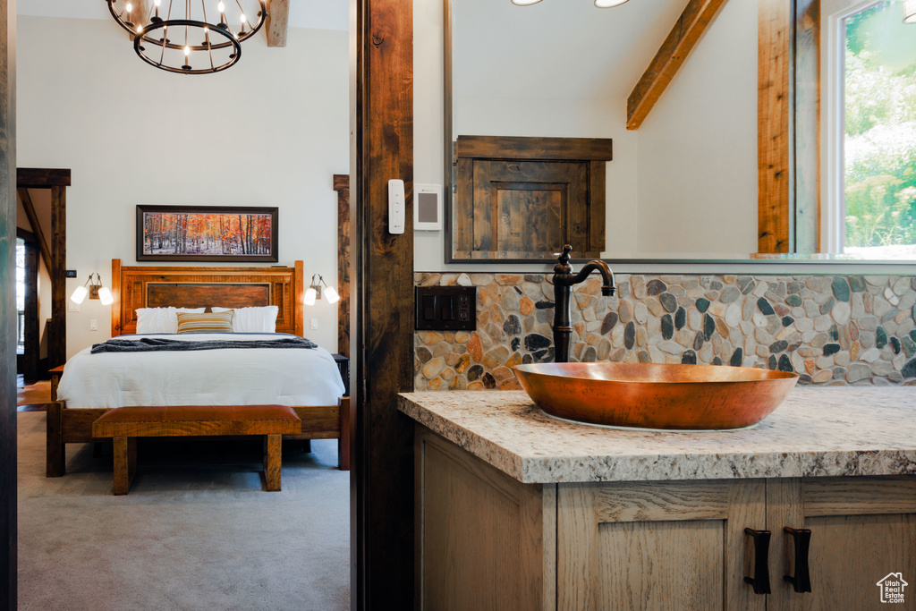 Bathroom with vanity, a chandelier, and beamed ceiling