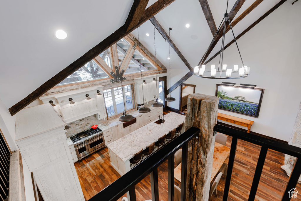 Living area featuring beamed ceiling, hardwood / wood-style floors, a chandelier, high vaulted ceiling, and recessed lighting