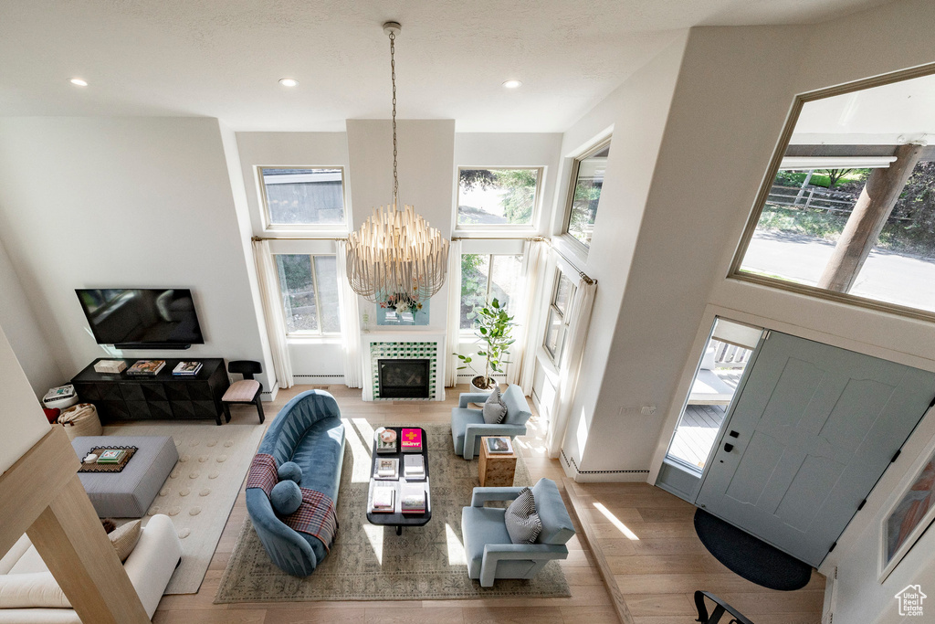 Living area with a chandelier, wood finished floors, a towering ceiling, and recessed lighting