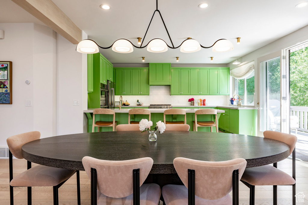 Kitchen featuring green cabinetry, light countertops, decorative backsplash, light wood finished floors, and recessed lighting