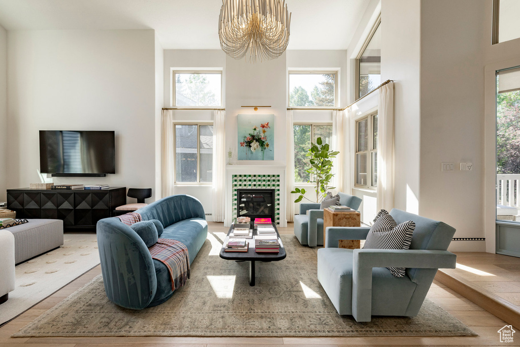 Living room with a chandelier, a towering ceiling, wood finished floors, and a fireplace