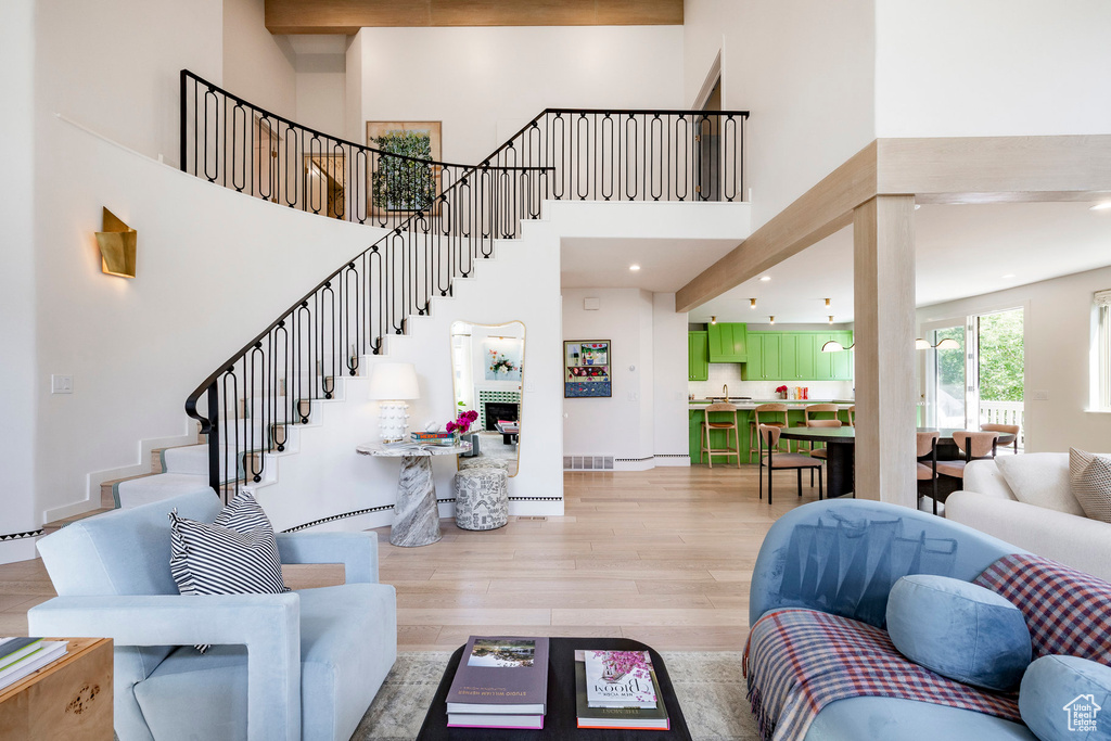 Living area featuring light wood-type flooring, a high ceiling, and stairs