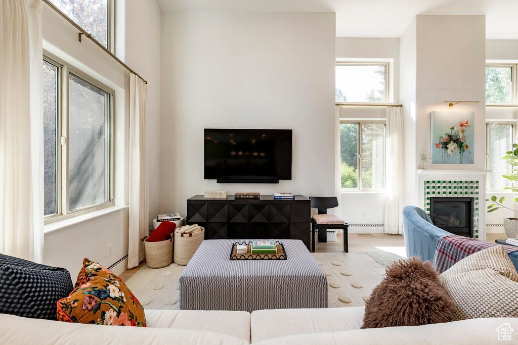 Living area with wood finished floors, a tiled fireplace, and a baseboard radiator