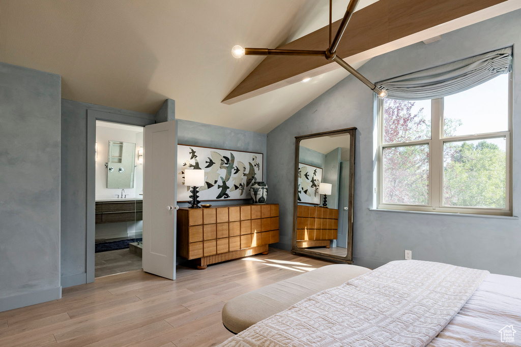 Bedroom with wood finished floors, lofted ceiling, and ensuite bathroom