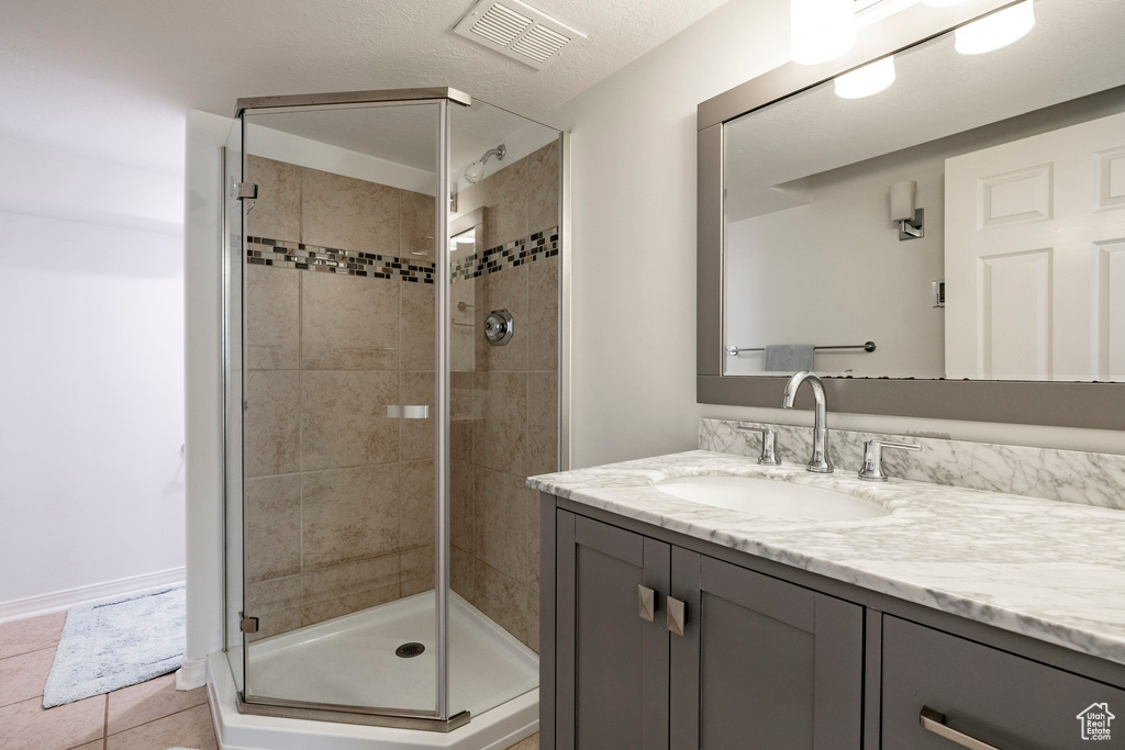 Full bath featuring vanity, a stall shower, and tile patterned flooring