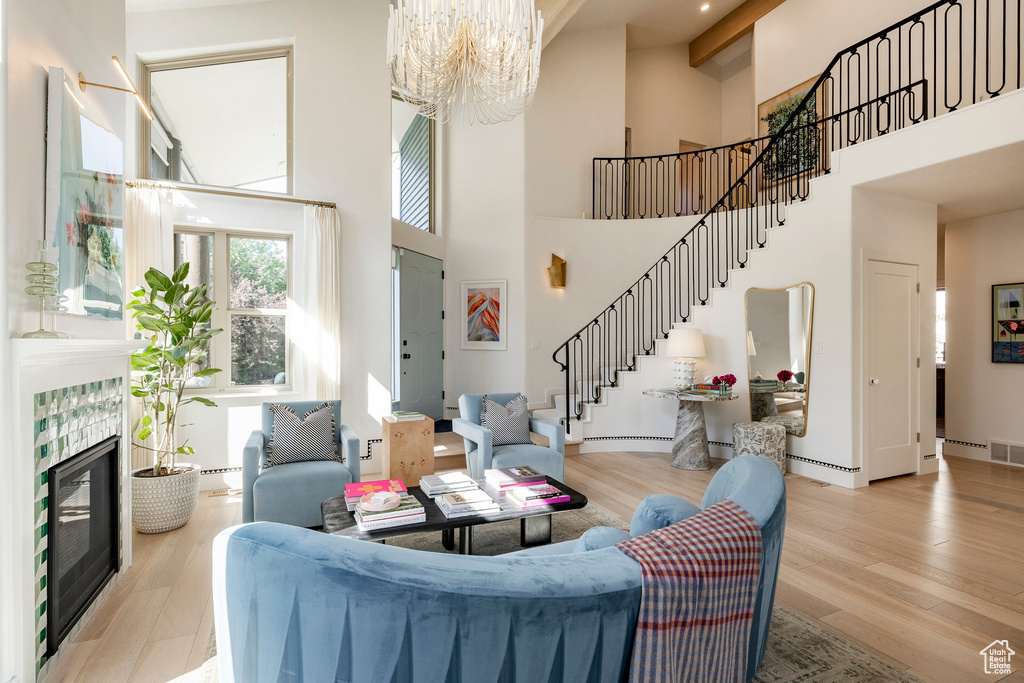 Living area featuring stairway, a high ceiling, a chandelier, light wood-style floors, and a fireplace