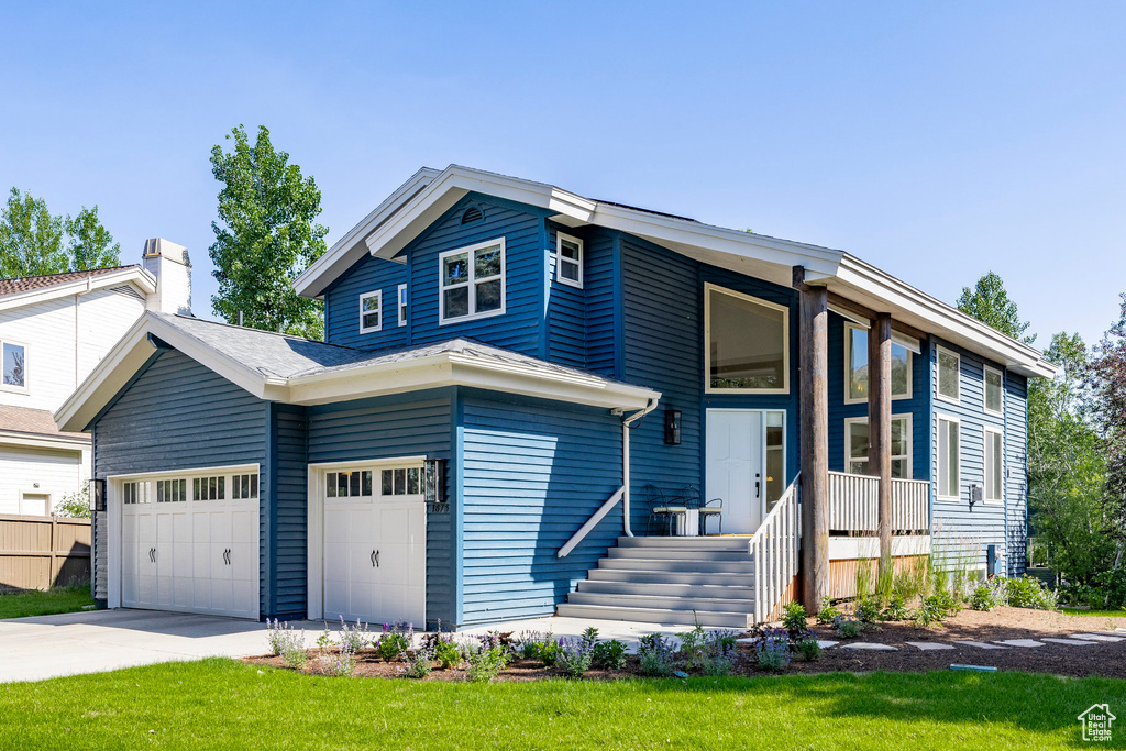 View of front of house featuring concrete driveway, an attached garage, and a front yard
