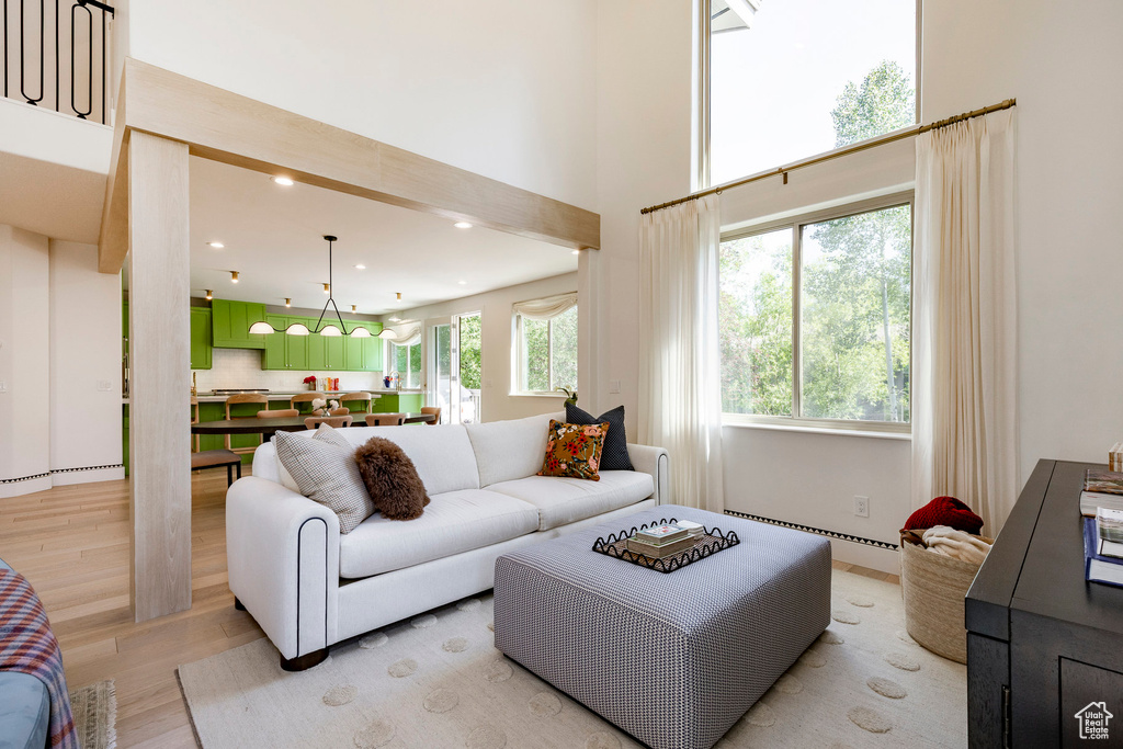Living area with light wood-type flooring, baseboard heating, recessed lighting, and a high ceiling