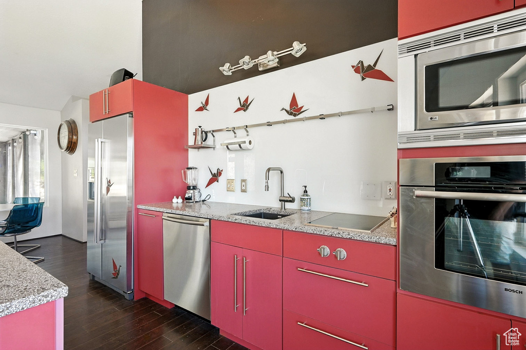 Kitchen featuring red cabinets, appliances with stainless steel finishes, dark wood-type flooring, light countertops, and yellow cabinetry