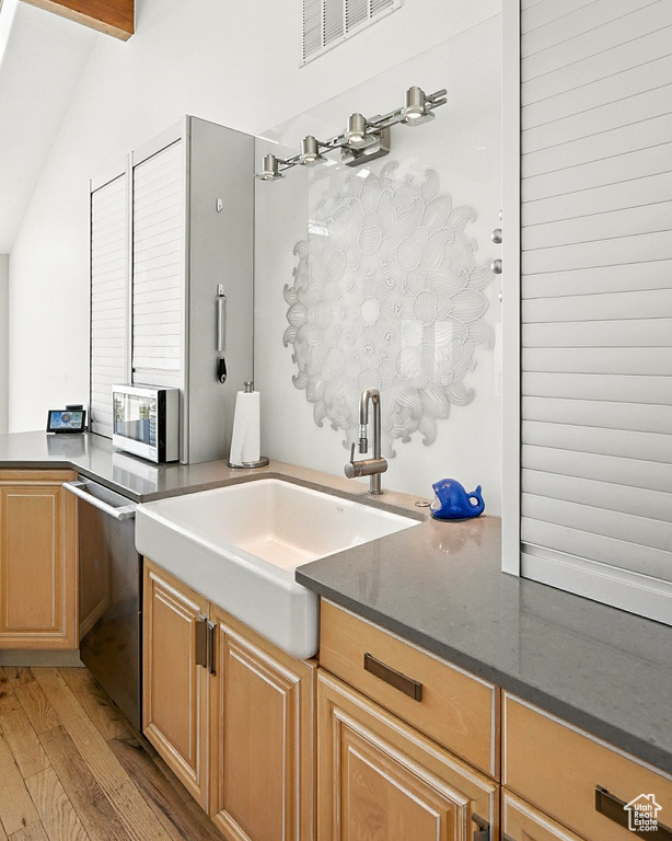 Kitchen featuring light wood-style floors, stainless steel appliances, dark stone counters, and lofted ceiling