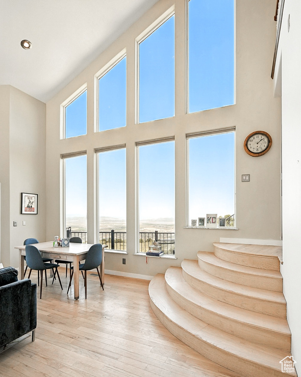 Living room with a high ceiling, light wood-type flooring, and stairs