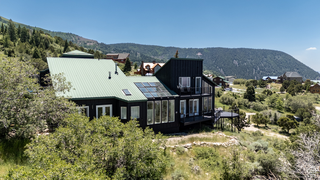 Back of house with a sunroom, a mountain view, a metal roof, board and batten siding, and a standing seam roof