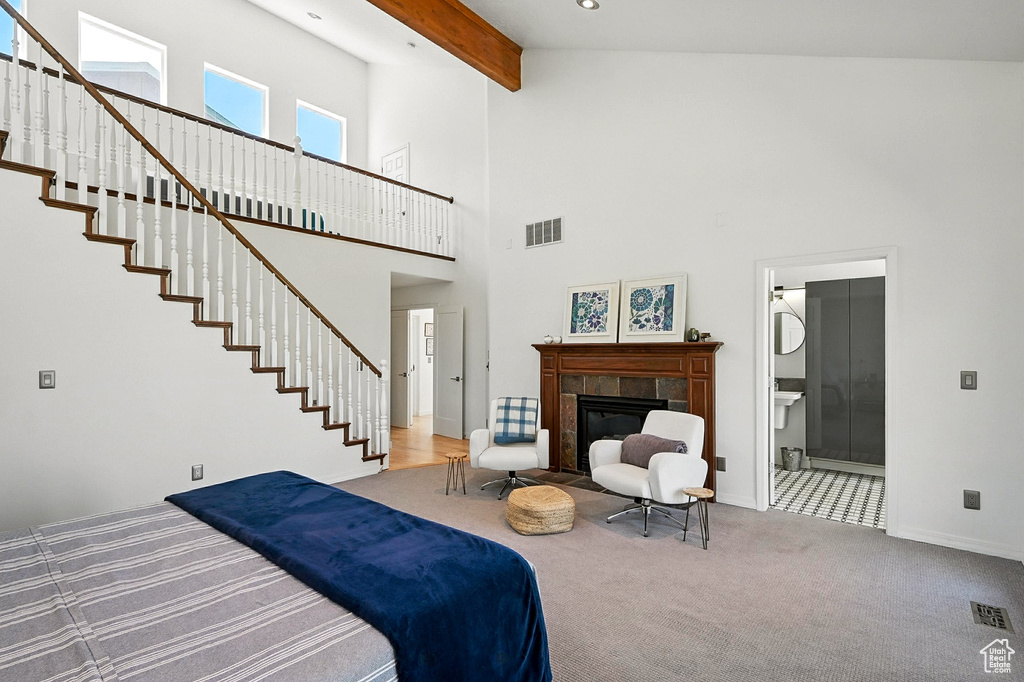 Carpeted bedroom with a tile fireplace, beamed ceiling, and a towering ceiling
