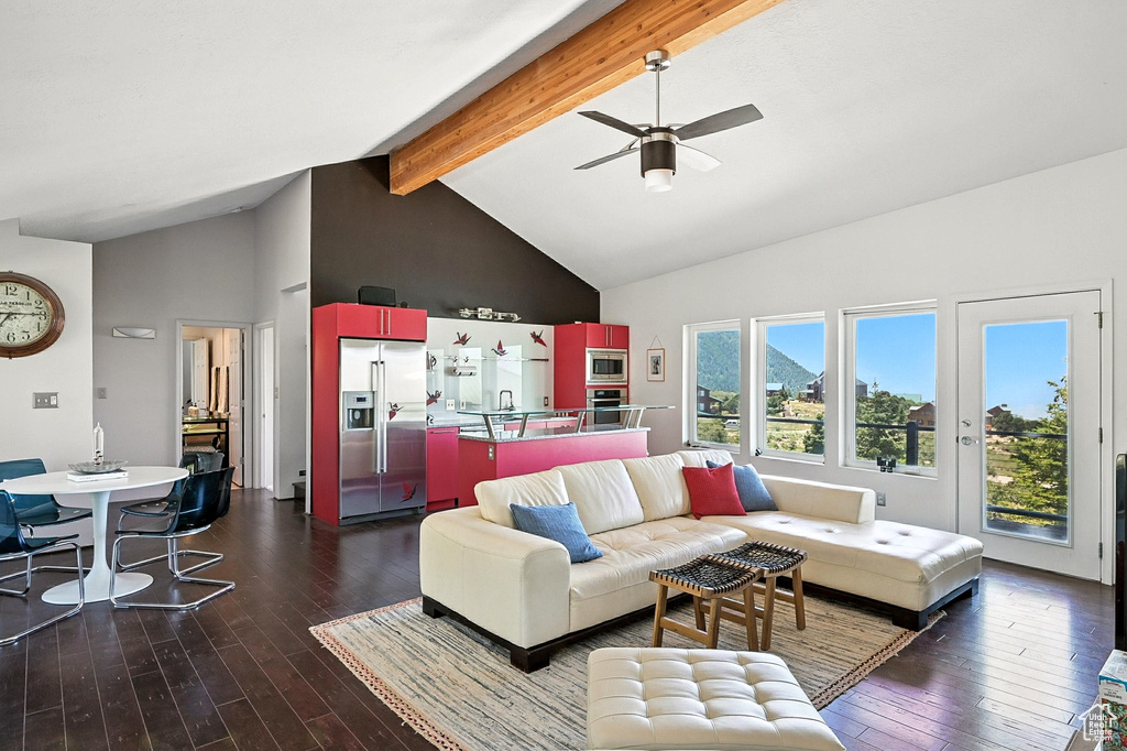 Living area featuring dark wood finished floors, beamed ceiling, high vaulted ceiling, and a ceiling fan