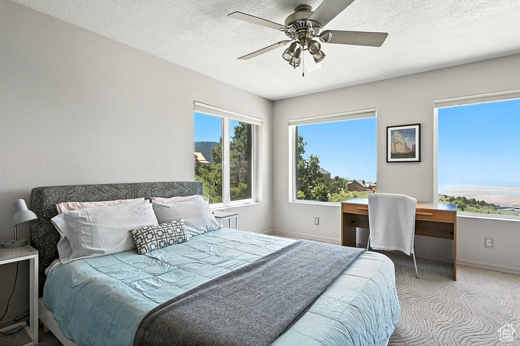 Carpeted bedroom featuring a desk, a textured ceiling, and a ceiling fan