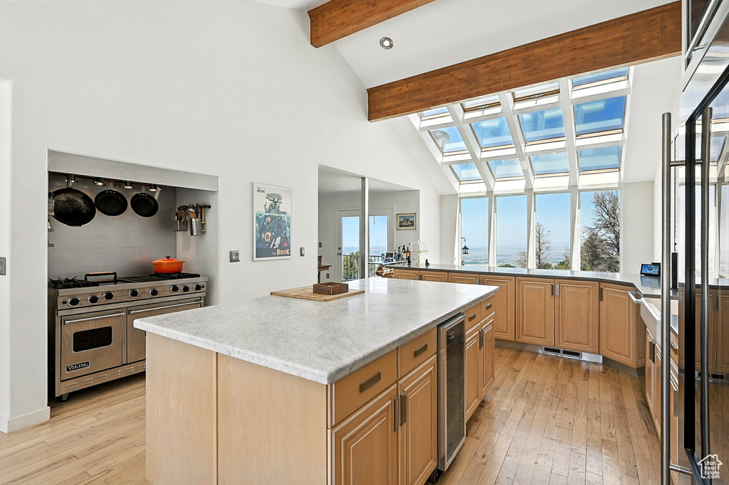 Kitchen with double oven range, light wood-type flooring, a skylight, a kitchen island, and beam ceiling